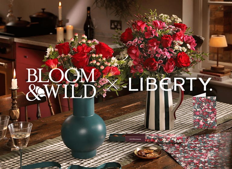 An assortment of vibrant bouquets, greetings cards and sweet treats are dotted across a kitchen surface. The Bloom & Wild and Liberty logos appear over the top.