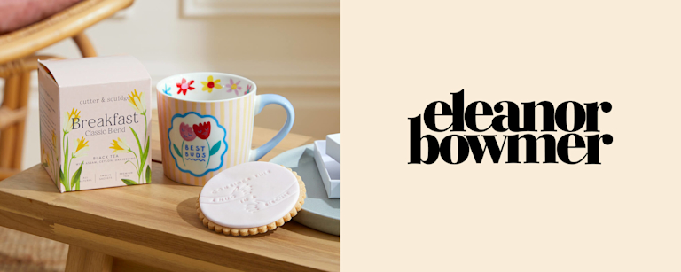 A painted ceramic mug with two tulips on, and the words 'Best buds', next to the Eleanor Bowmer logo