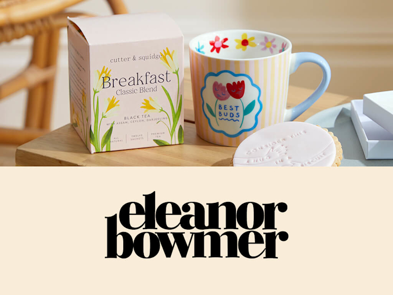 A painted ceramic mug with two tulips on, and the words 'Best buds', next to the Eleanor Bowmer logo