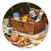 A wicker hamper and selection of snacks on a table