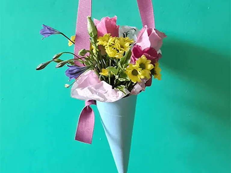Ein Blumenstrauß in einer Schultütenförmigen Vase aus Bastelpapier