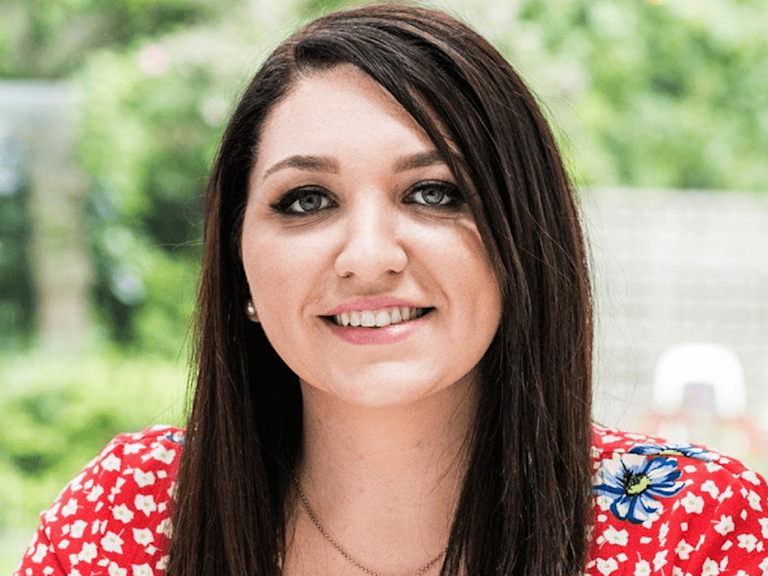 Rochelle, a light-skinned woman with long brown hair and blue eyes, gazes out with a kind smile.