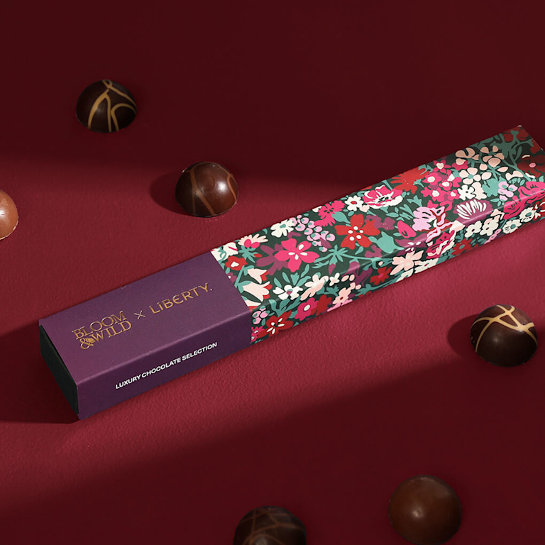 A box, decorated with a Liberty print, sits in the middle of assorted chocolates.