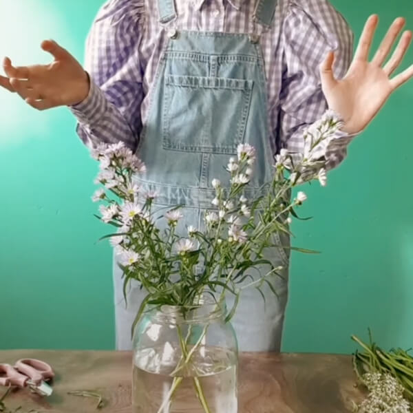 Harriet places the stems in a glass vase in a criss-cross shape.