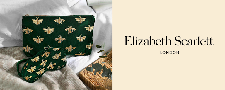A dark green velvet pouch and eye mask, embroidered in gold honeybees.