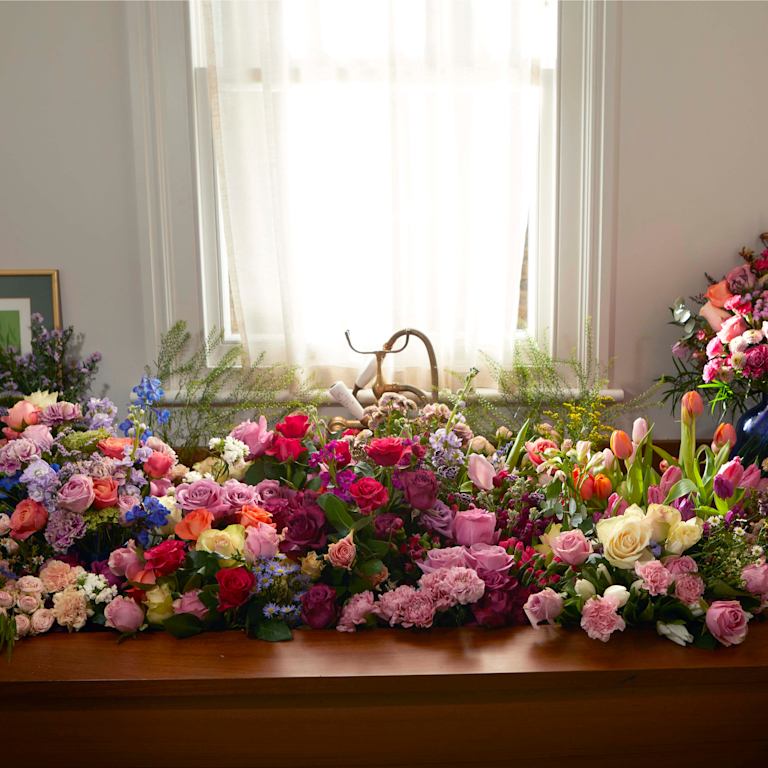 abundant peonies, tulips, and roses arranged in a sink