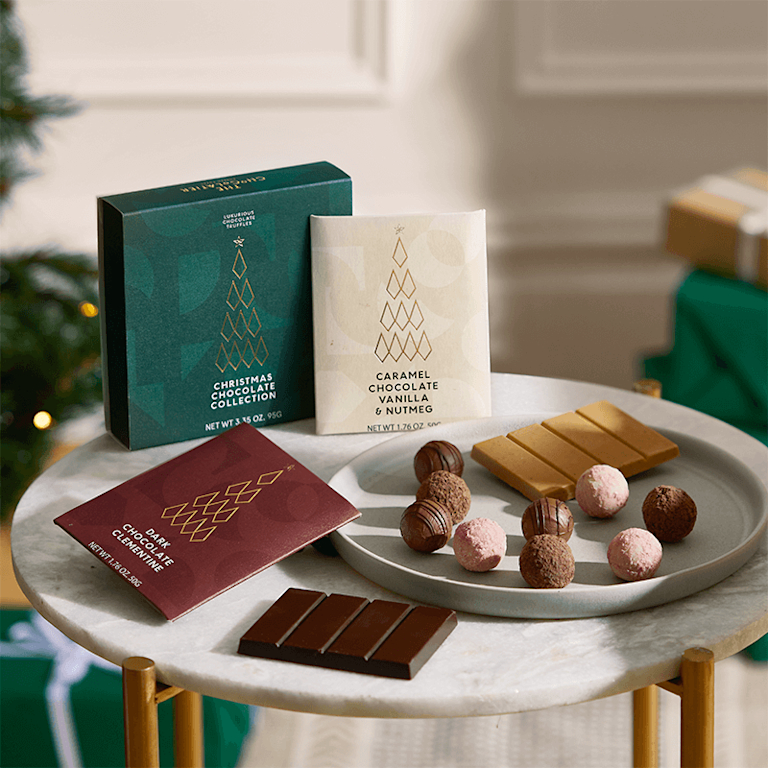 A selection of tempting chocolate truffles on a plate, along with chocolate bars and swish gold-foiled packaging in muted festive colours.