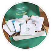 An open green letterbox gift box showing greeting cards and wellbeing treats inside.