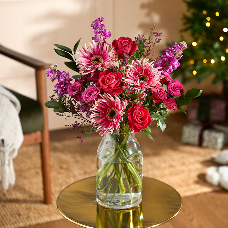 The Gabi bouquet with pink roses and gerberas on a side table