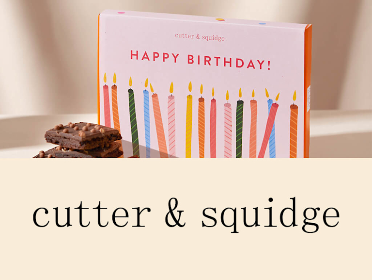 A box of brownies with the message 'Happy birthday!' on, next to Cutter & Squidge's logo.