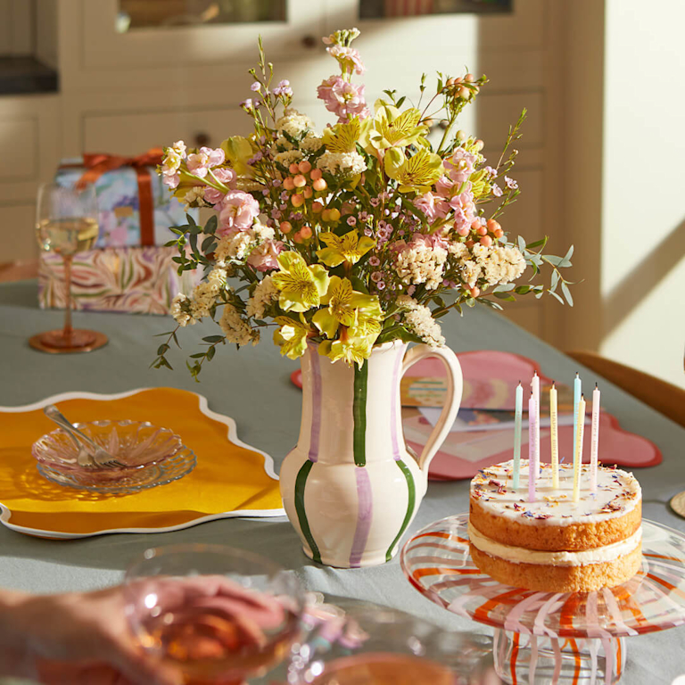Flowers in jug on table with birthday decorations