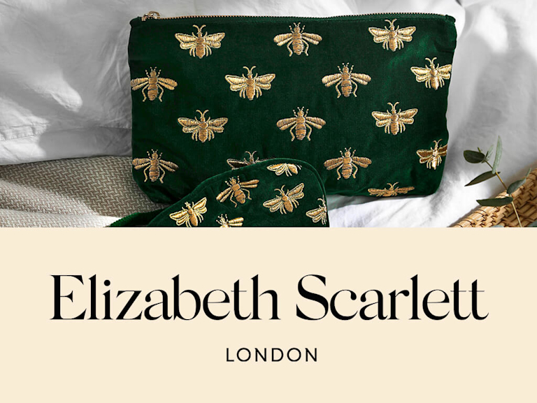 A dark green velvet pouch and eye mask, embroidered in gold honeybees.