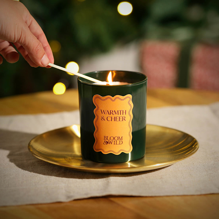 A green candle sits on a gold plate.