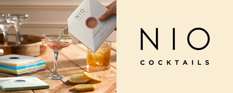 Someone pours a cocktail from a packet into a coupé glass. Text says 'NIO Cocktails'.