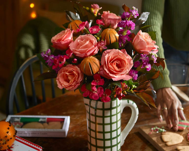 The Bloom & Wild Joni bouquet, with pink flowers, and orange peel. Arranged in a green and white vase.