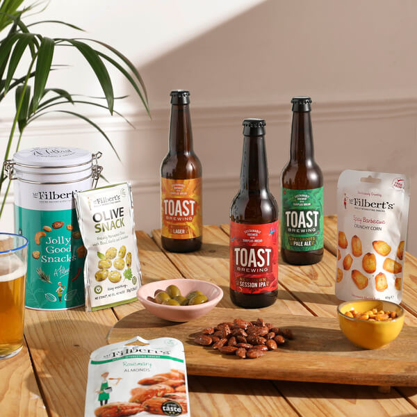 A trio of Toast beers, surrounded by Mr. Filberts snacks including nuts and olives.