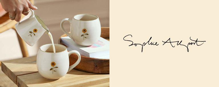 Two classy white ceramic mugs and a milk jug, with a simple and stylish sunflower painted on them.