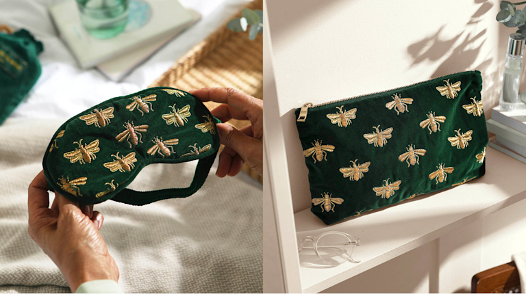 A dark green velvet eye mask and pouch, both embroidered with gold honeybees.