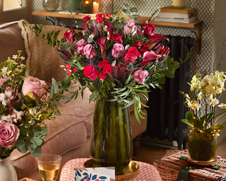 Bloom & Wild Firth Bouquet in a dark green glass vase, featuring pink an burgundy stems