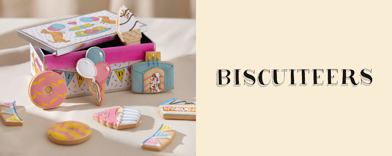 Two images. The first shows a mix of iced biscuits, decorated to look like party items (i.e balloons and birthday cake), placed around a celebratory tin. The second is of Biscuiteers' logo on a linen background.
