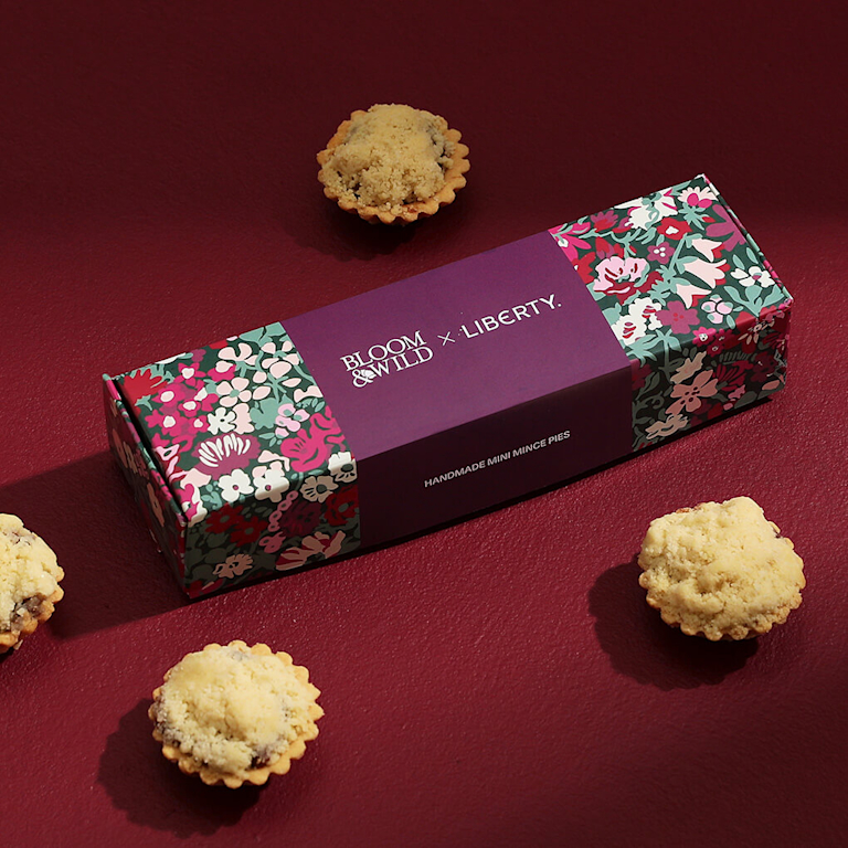 A box, decorated with a Liberty print, sits in the middle of four mini mince pies.