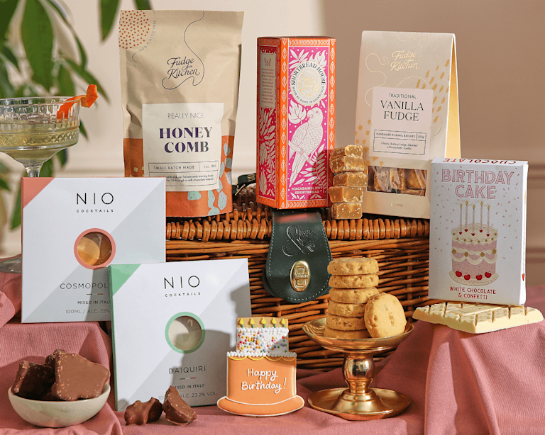 Wicker hamper with NIO Cosmopolitan and Daiquiri cocktails, honeycomb, vanilla fudge, macadamia shortbread, birthday cake white chocolate, a Happy Birthday iced biscuit and chocolate honeycomb.