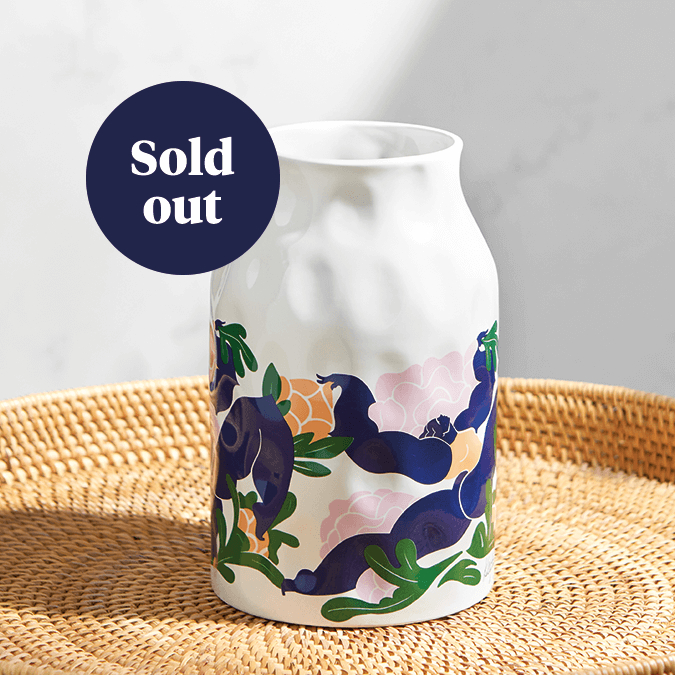 The Kelly Anna vase. A white ceramic vase with a wide neck, printed with a bold, abstract design depicting a female figure leaping among several peach and pink peonies. A label on the image says 'Sold out'