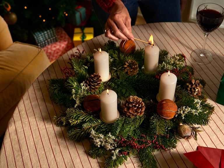Ein festlich geschmückter Adventskranz mit vier brennenden Kerzen.