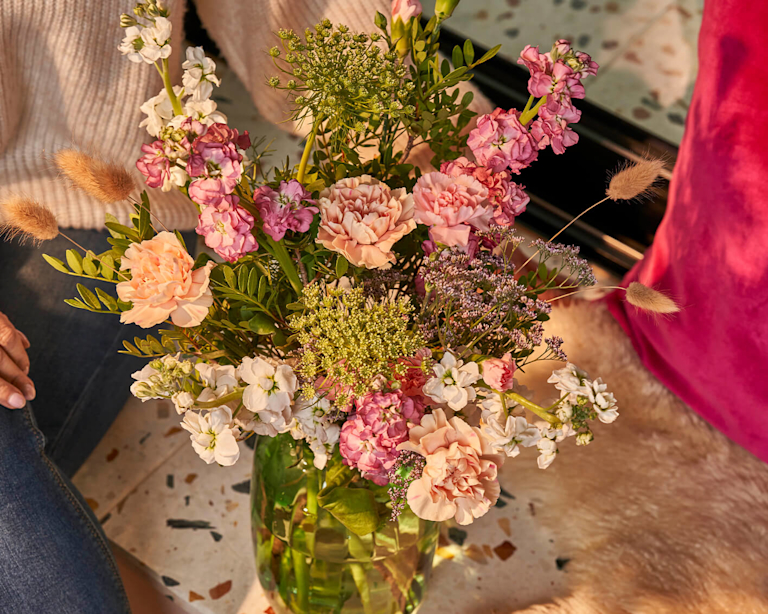An artfully arranged bouquet of meadowy spring stems, like stocks, ammi, bunny tail grass and carnations.