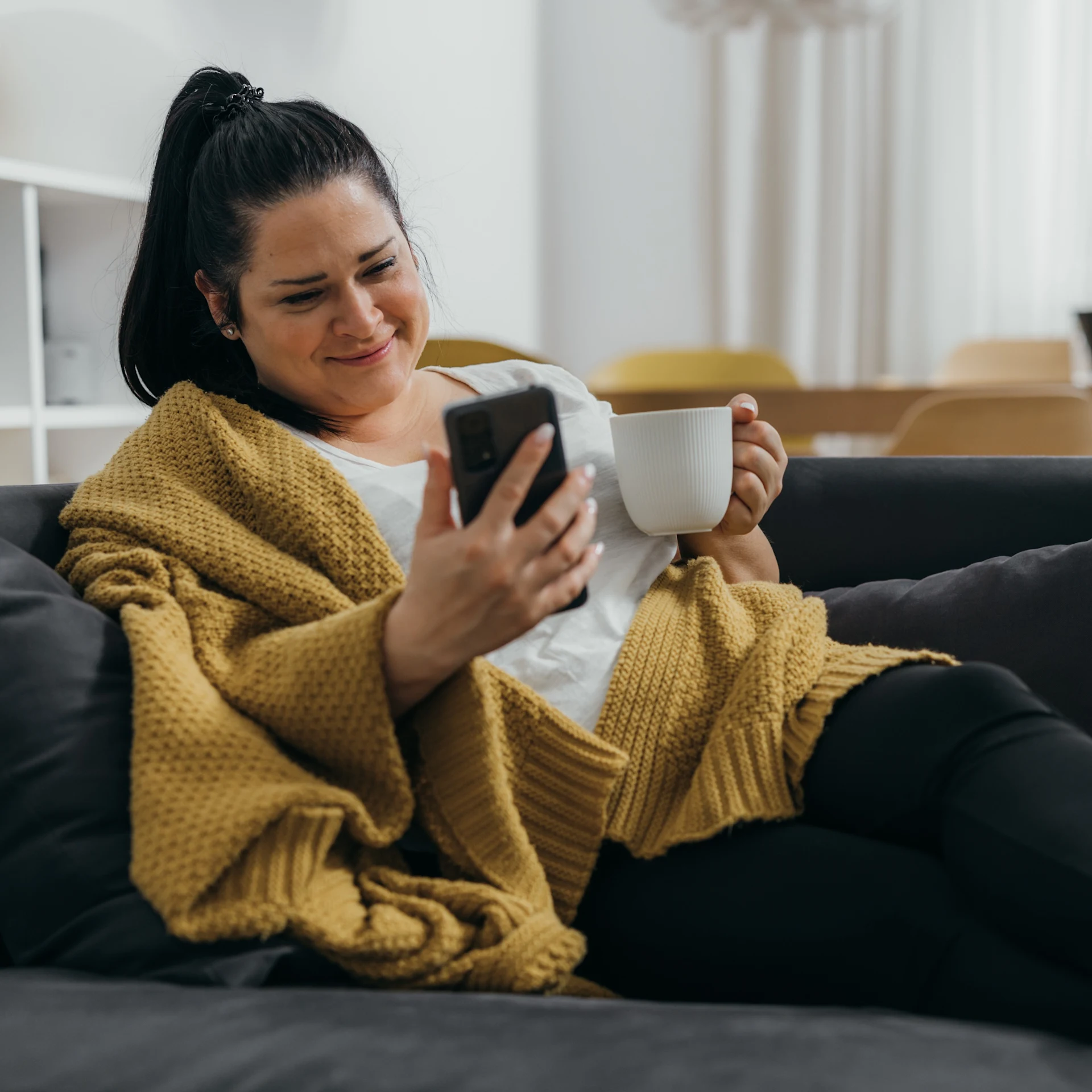 sick woman on couch looking at phone