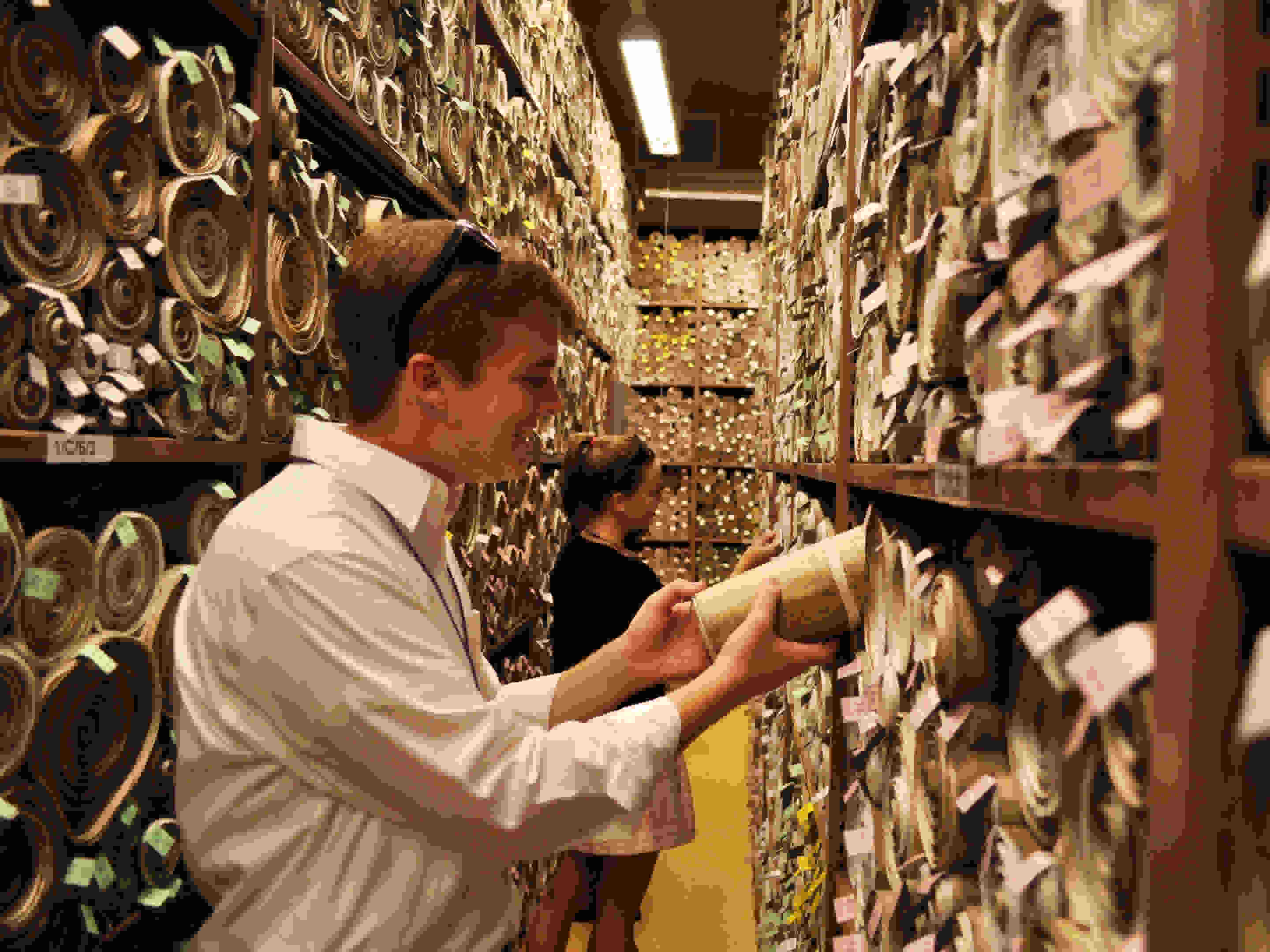 Photo of Hansard Society Scholars sifting through scrolls of historic Acts of Parliament in the Parliamentary Archives, UK Houses of Parliament