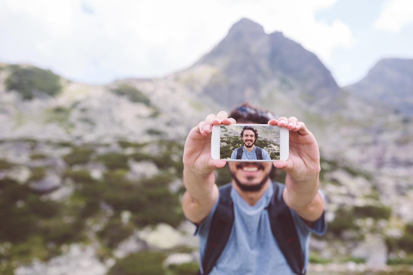 Man on mountain taking selfie