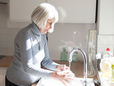 Elderly woman washing dishes in the sink