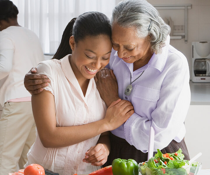 A grandmother and her granddaughter embracing as they prepare food