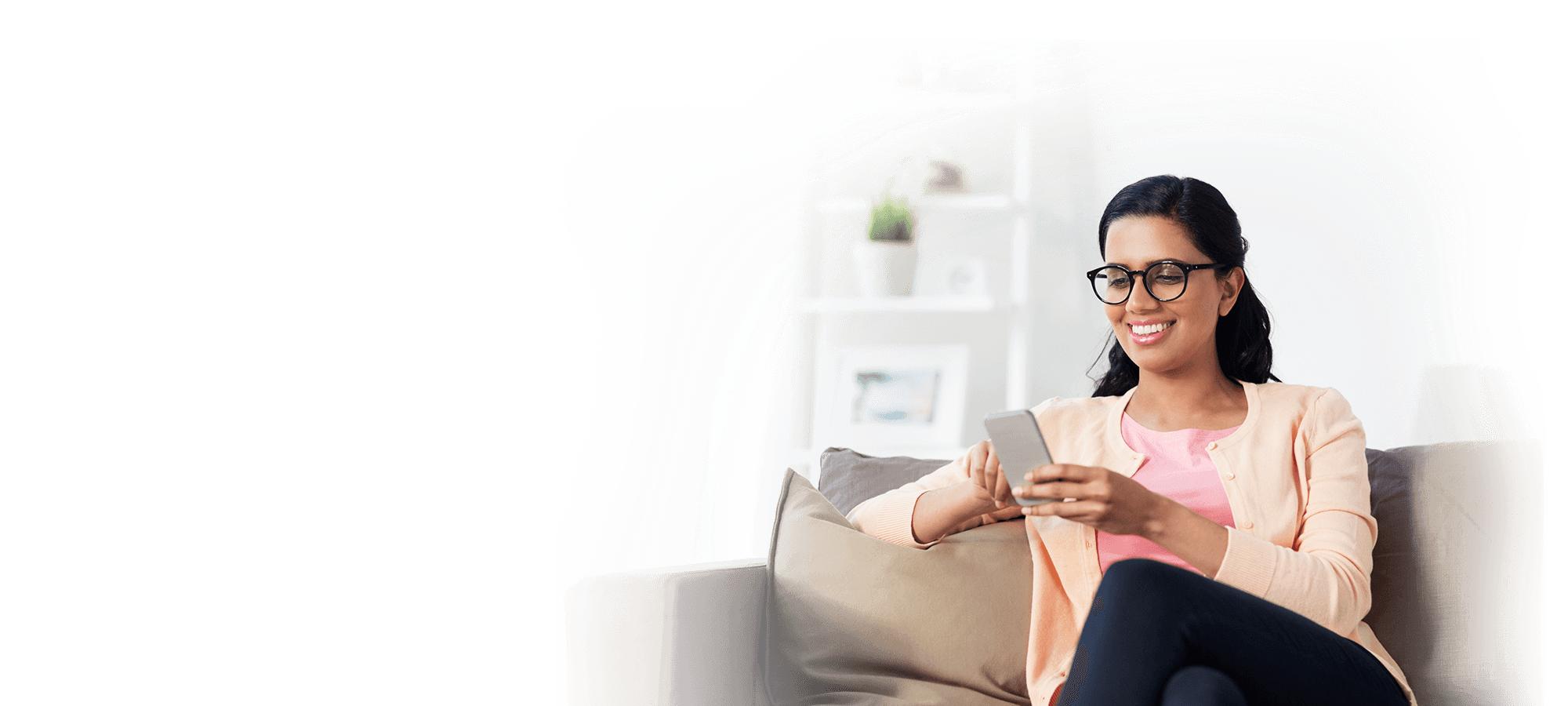 Smiling woman sitting on her couch looking at her phone.