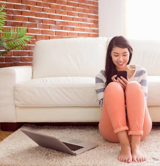 Woman sitting on her living room floor looking at her phone
