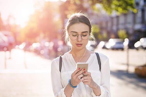 A girl walking down the street looking at her phone