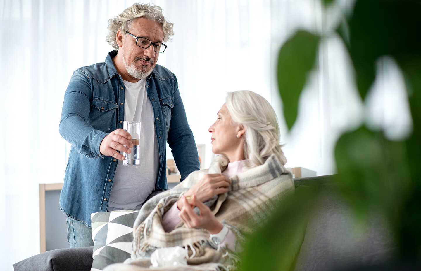 A man giving a glass of water to an elderly woman