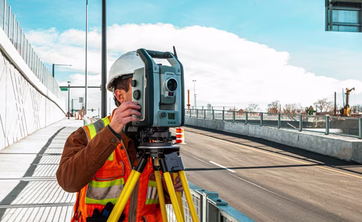 Topógrafo trabaja junto a una carretera y utiliza una estación total Trimble.