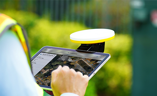 A smart tablet (running Esri ArcGIS Field Maps on the screen) attached to the Trimble Catalyst Handle accessory with Trimble DA2 receiver.