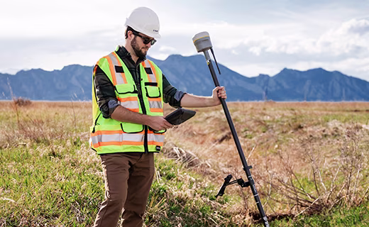 Un topógrafo mide puntos en un entorno rural aprovechando la función de compensación de inclinación del Trimble R980.