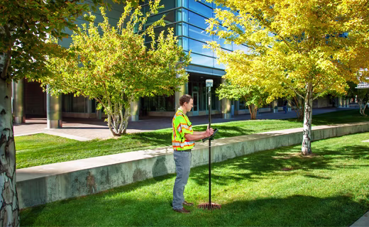 géomètre à côté d'un bâtiment avec un mobile GNSS