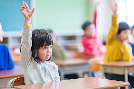 Child raising her hand in school classroom