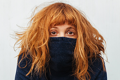 Woman covering face with sweater