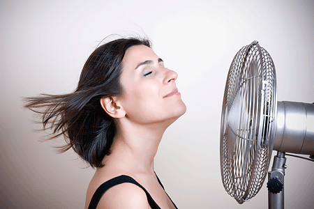 A fan blowing a woman's short brown hair behind her