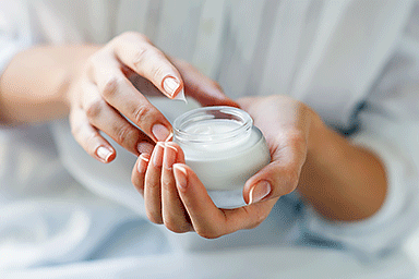 Close-up of woman holding a glass jar of skin cream.