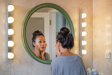 Woman looking in mirror at her face