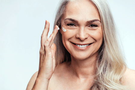 Woman applying cream to her face