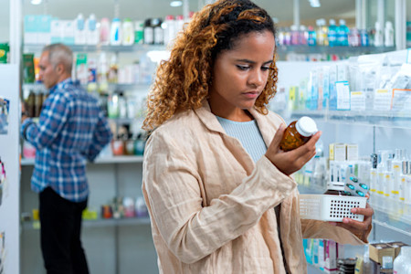 Woman shopping for vitamins in a store looks at ingredient list