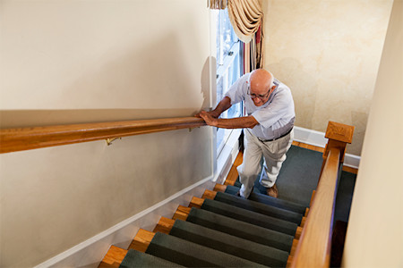 Man in his 70s feels intense pain while walking up stairs in his home due to nail fungus on his toenails.